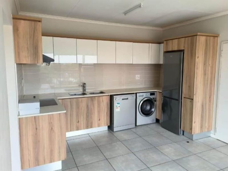 Modern kitchen featuring wood-grain and white cabinetry, tiled flooring, integrated sink, and dedicated spaces for appliances.