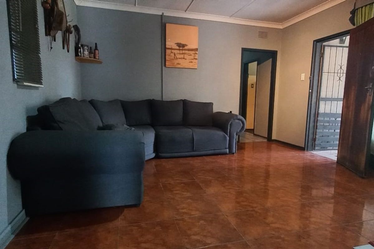 A living room featuring tiled flooring, coved ceilings, and a security gate at the entrance.