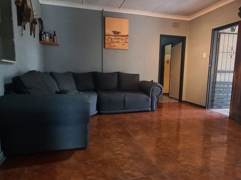 A living room featuring tiled flooring, coved ceilings, and a security gate at the entrance.