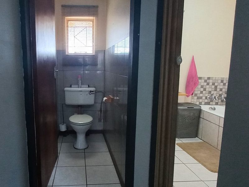 A functional bathroom featuring a separate toilet area and a bathtub with tiled finishes.