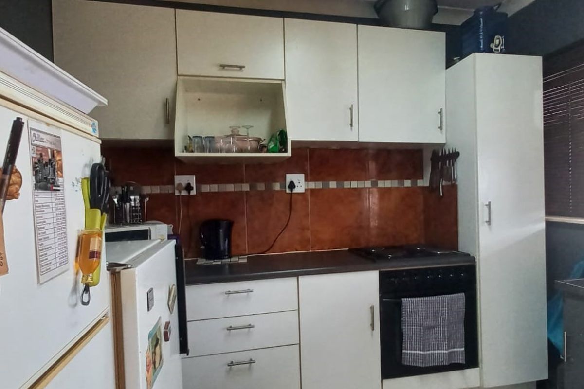 A functional kitchen featuring white cabinetry, dark laminate countertops, a tiled backsplash, and a built-in oven with a hob.