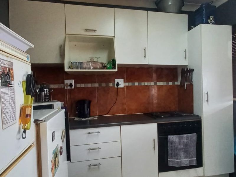 A functional kitchen featuring white cabinetry, dark laminate countertops, a tiled backsplash, and a built-in oven with a hob.