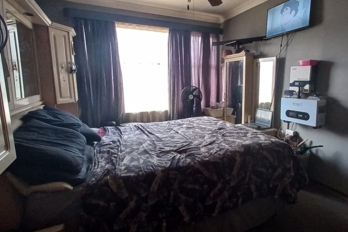 A bedroom featuring built-in cabinetry, a ceiling fan, and a wall-mounted solar inverter system.