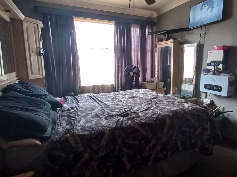 A bedroom featuring built-in cabinetry, a ceiling fan, and a wall-mounted solar inverter system.