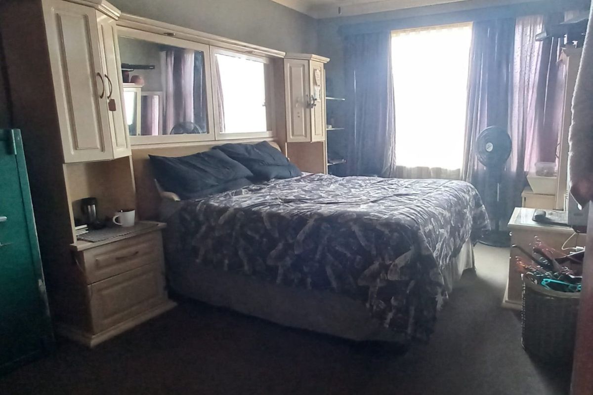 A bedroom featuring built-in cabinetry with integrated mirrors and a ceiling fan, providing functional storage and lighting.