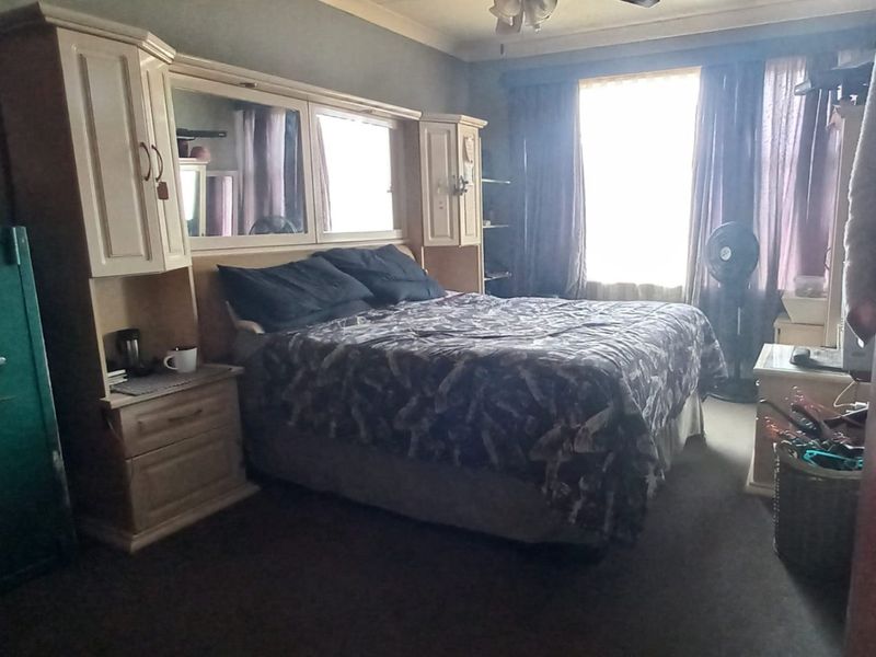 A bedroom featuring built-in cabinetry with integrated mirrors and a ceiling fan, providing functional storage and lighting.