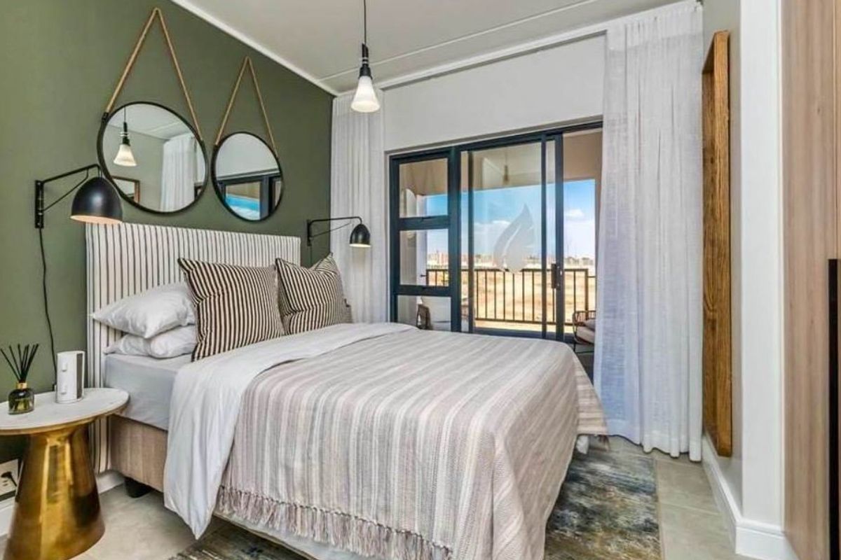 A well-maintained bedroom featuring a feature wall, built-in wardrobe, and sliding glass doors providing access to a private balcony.