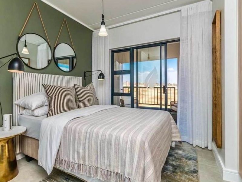 A well-maintained bedroom featuring a feature wall, built-in wardrobe, and sliding glass doors providing access to a private balcony.