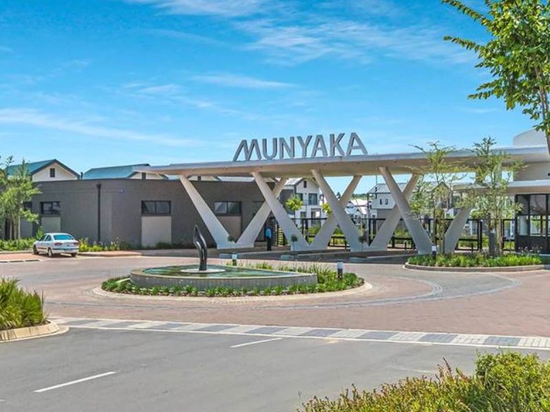 The main entrance to the Munyaka estate featuring a modern architectural gatehouse, paved circular driveway, and a central water feature.