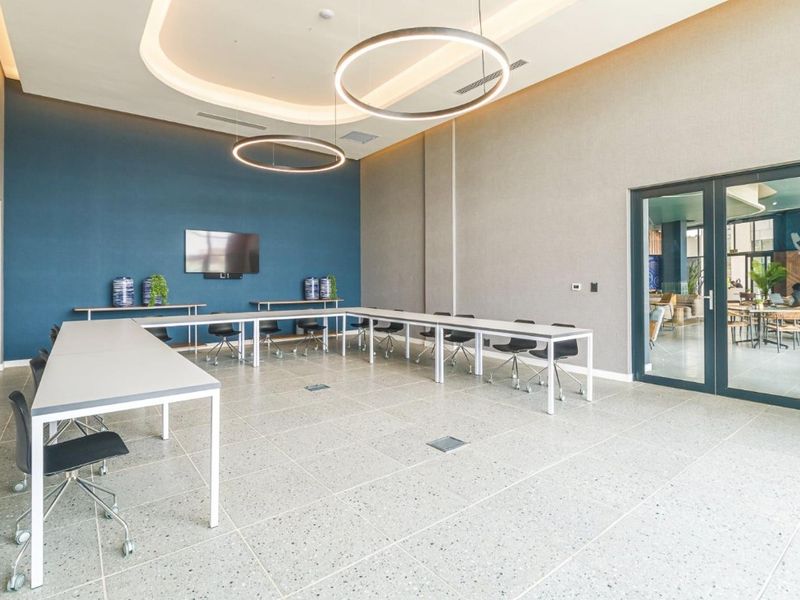 A modern, well-maintained clubhouse or meeting space featuring high ceilings, recessed lighting, a blue feature wall, and large glass doors.