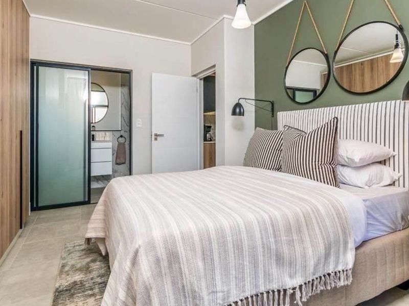 A modern, well-maintained bedroom featuring built-in cupboards, tiled flooring, and direct access to an en-suite bathroom with a sliding door.
