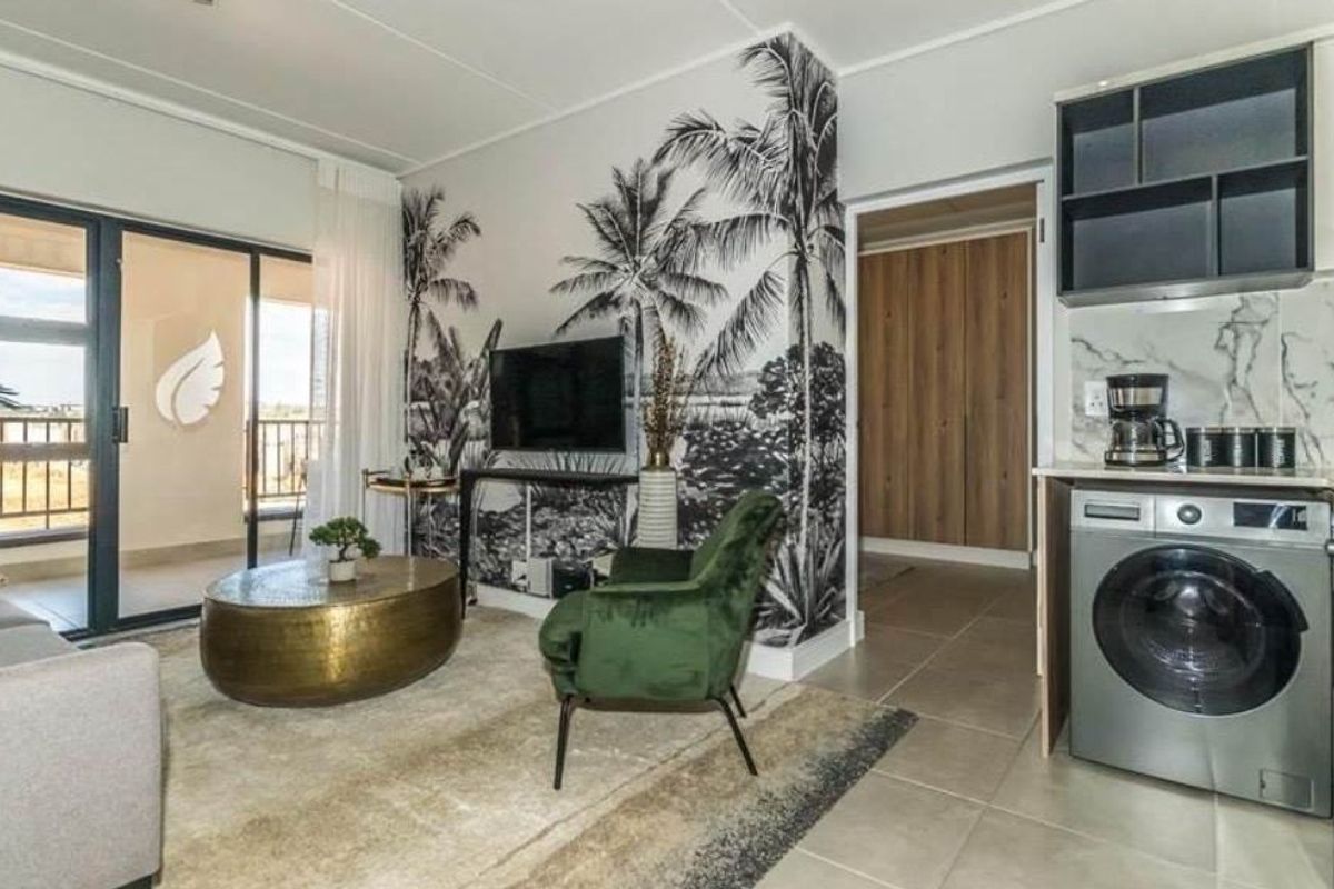 Modern open-plan living area featuring a compact kitchen with integrated laundry, tiled floors, and direct access to a private balcony.