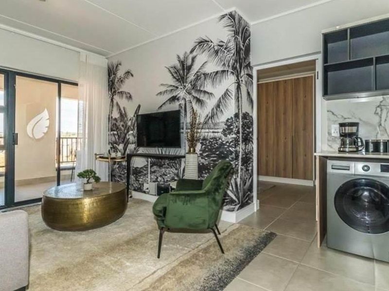 Modern open-plan living area featuring a compact kitchen with integrated laundry, tiled floors, and direct access to a private balcony.