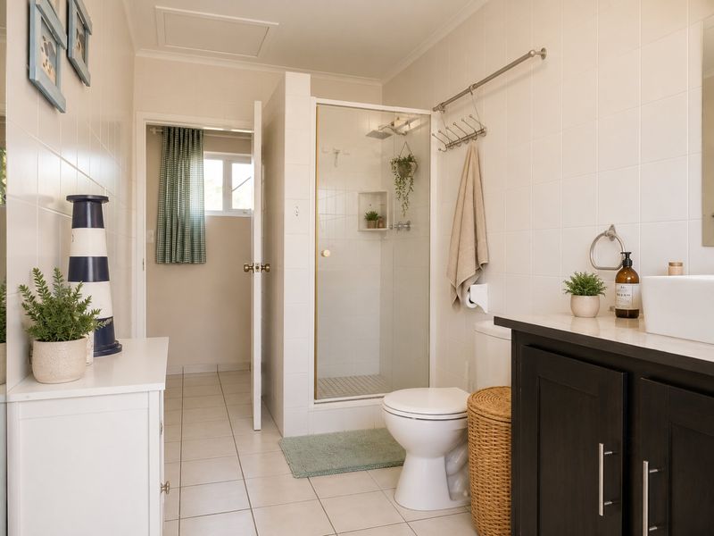 A clean, well-maintained bathroom featuring a glass-enclosed shower, modern vanity with countertop basin, and neutral wall tiling.