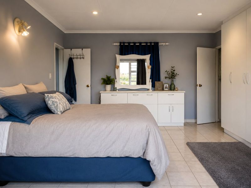 A well-maintained bedroom featuring neutral tiled flooring, built-in cupboards, and recessed ceiling lighting, creating a clean and functional living space.