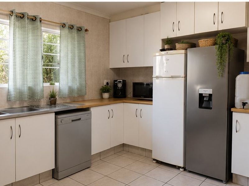 A functional kitchen featuring white built-in cabinetry, laminate countertops, tiled backsplash, and tiled flooring with a window providing natural light.