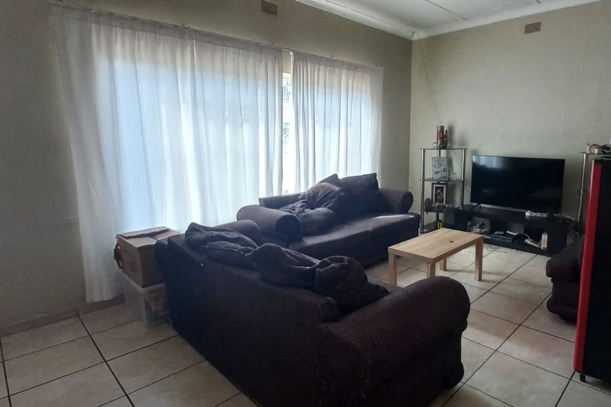 A functional living room featuring tiled flooring and a large sliding glass door that provides natural light.