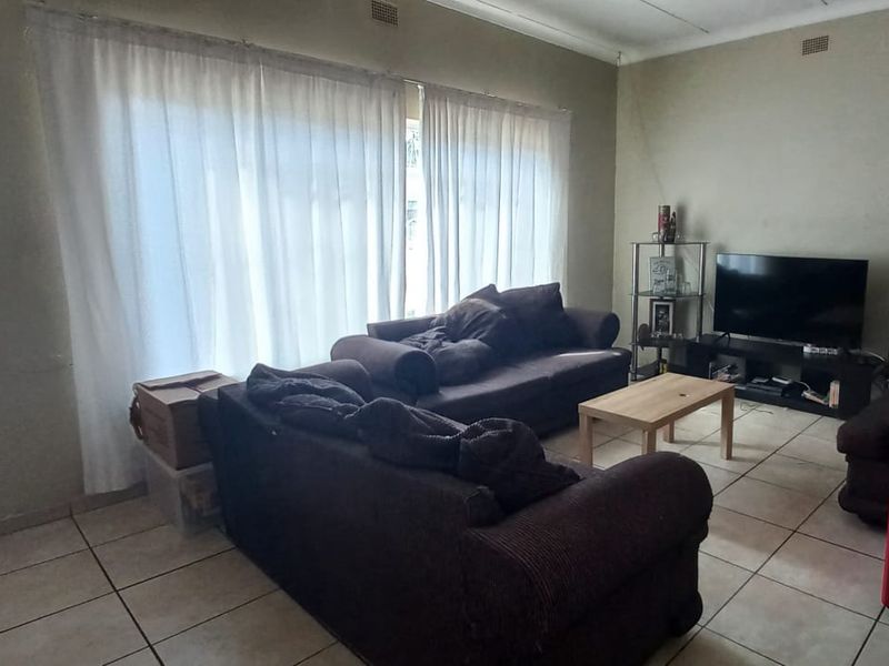 A functional living room featuring tiled flooring and a large sliding glass door that provides natural light.