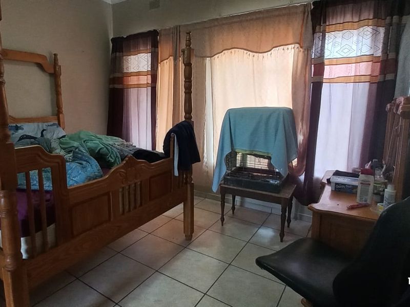 A bedroom featuring tiled flooring and window treatments, providing a functional space for rest.