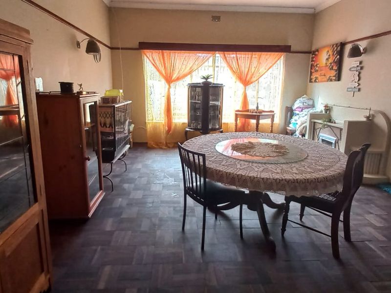 A dining room featuring original parquet flooring, a built-in fireplace, and a picture rail, offering a traditional layout with potential for modernization.