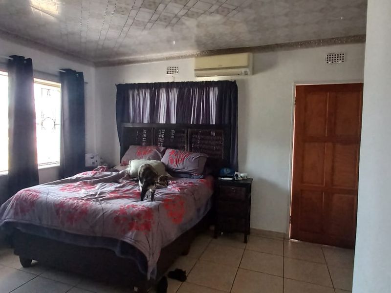 A bedroom featuring tiled flooring, a textured ceiling, and a wall-mounted split-system air conditioner.