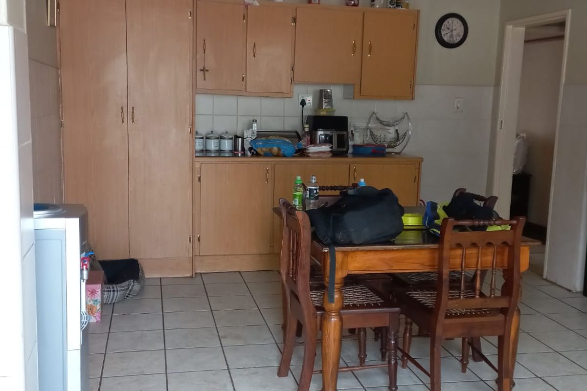 A functional kitchen featuring built-in wooden cabinetry, tiled flooring, and a freestanding stove, offering a practical layout for daily meal preparation.