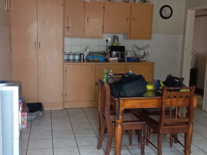 A functional kitchen featuring built-in wooden cabinetry, tiled flooring, and a freestanding stove, offering a practical layout for daily meal preparation.
