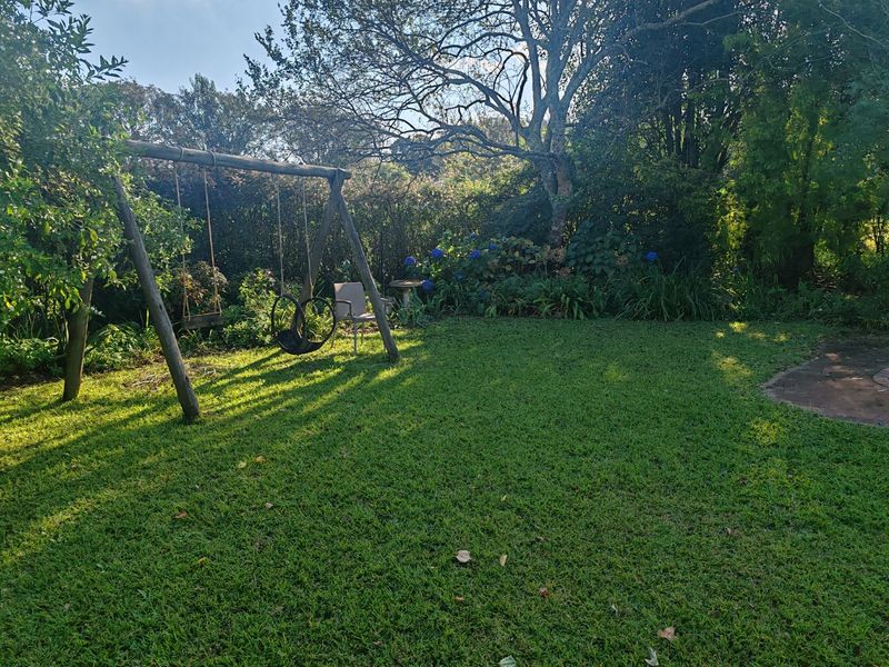 A well-maintained private garden featuring a lush green lawn, mature trees, and established garden beds, providing a peaceful outdoor space.