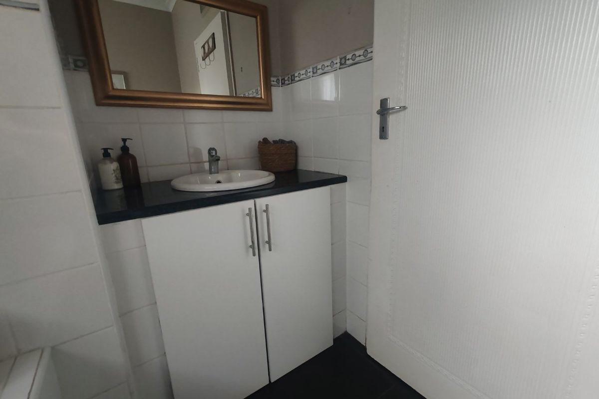 A functional bathroom featuring a vanity cabinet with a basin, tiled splashback, and a wall-mounted mirror.