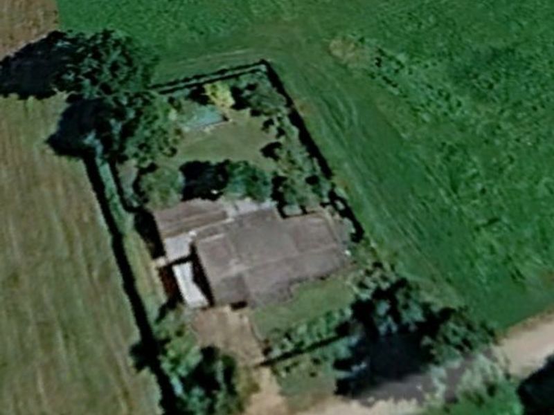 An aerial view of a residential property featuring a private swimming pool, landscaped garden, and driveway, situated within a rural or semi-rural setting.