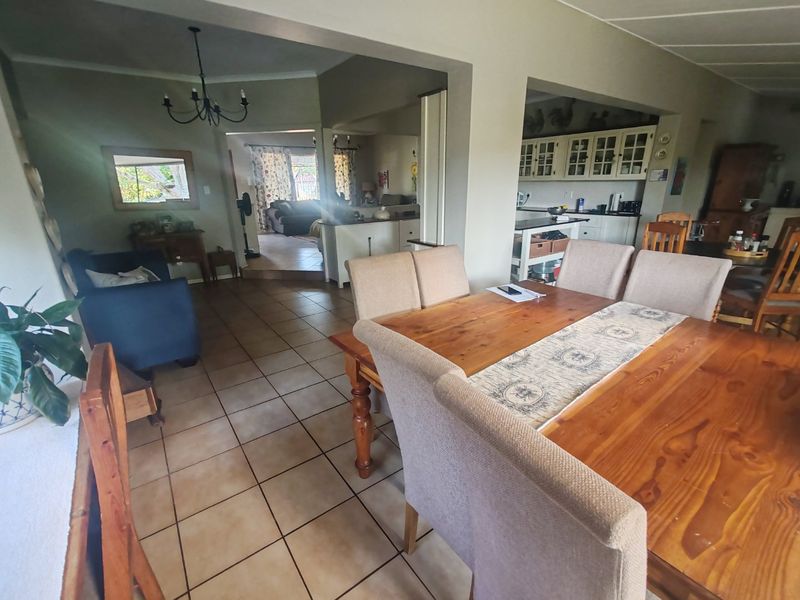 Spacious open-plan living and dining area featuring tiled flooring, flowing into a functional kitchen with built-in cabinetry and a central island.