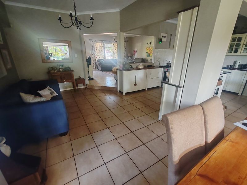 Open-plan living and kitchen area featuring ceramic tile flooring, a central kitchen island, and a connected layout leading to an adjacent lounge space.