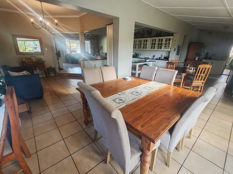 Spacious open-plan living and dining area featuring tiled flooring and a connected kitchen with built-in cabinetry.