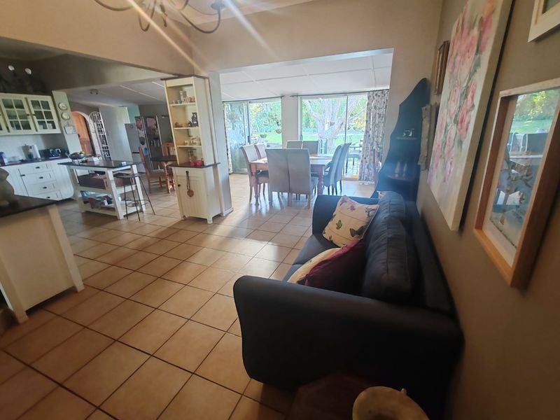 Open-plan living and kitchen area featuring tiled flooring, built-in cabinetry, and large sliding glass doors providing access to the garden.