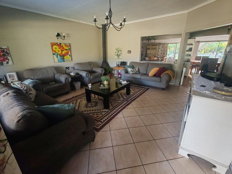 Spacious open-plan living area featuring ceramic tile flooring, a central freestanding fireplace, and a coved ceiling with decorative lighting.