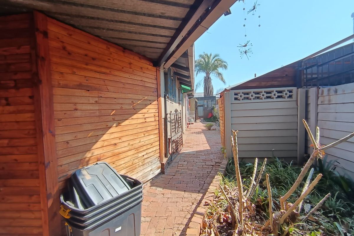 A side walkway featuring brick paving, timber wall cladding, and a covered roof overhang leading toward the rear garden area.