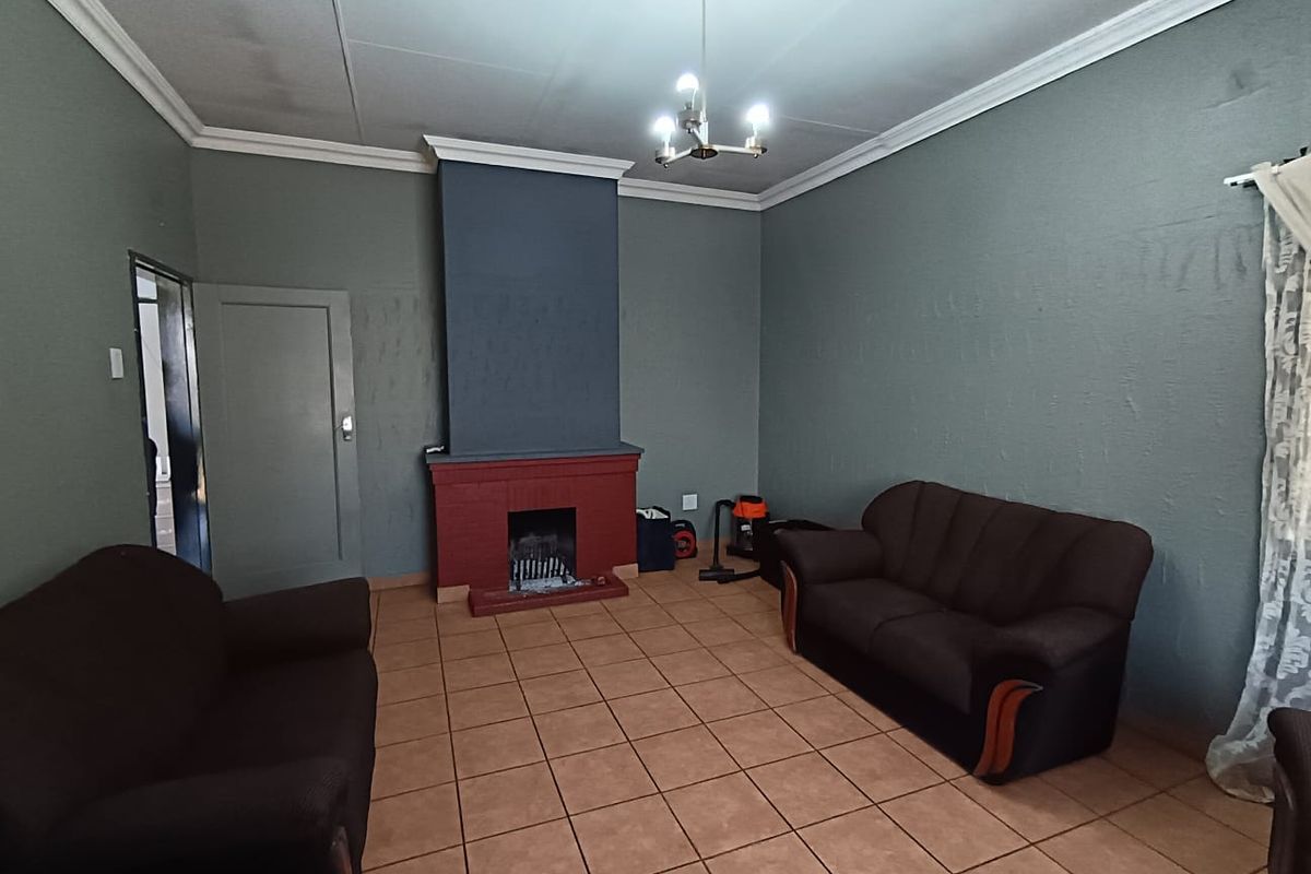 A living room featuring a central brick fireplace, tiled flooring, and decorative ceiling cornices.