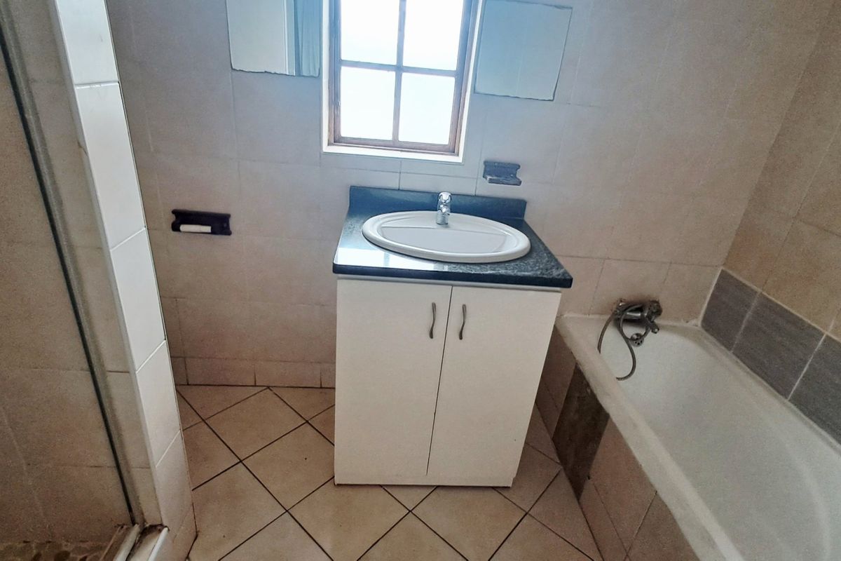 A functional bathroom featuring a vanity cabinet with basin, a bathtub, and a separate shower enclosure with tiled finishes throughout.