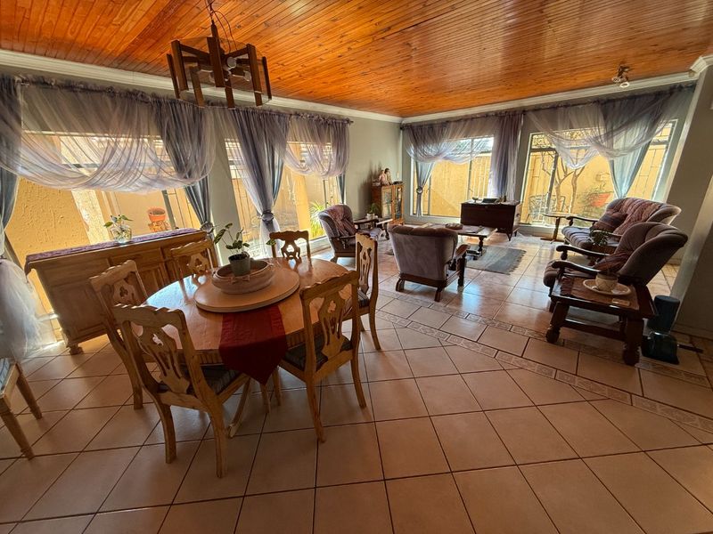 Spacious open-plan living and dining area featuring a warm timber tongue and groove ceiling and large windows providing ample natural light.