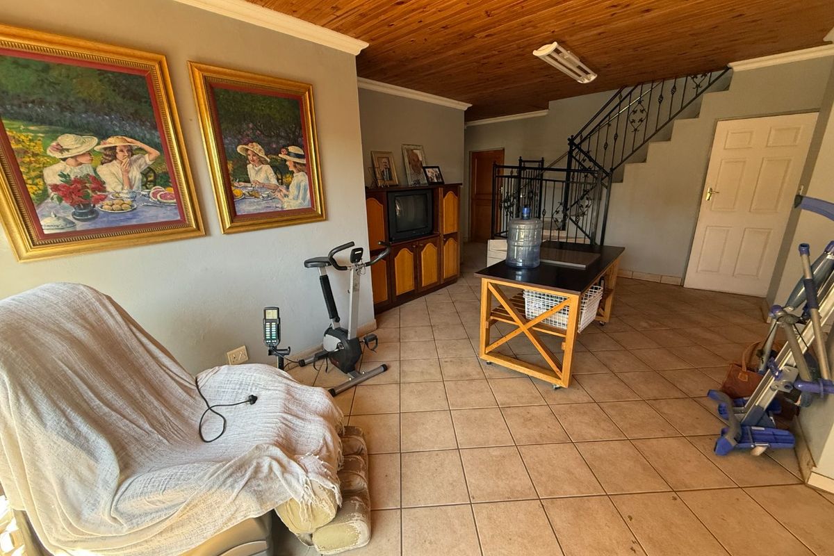 Living area featuring a timber ceiling, ceramic tiled flooring, and a wrought iron staircase railing leading to the upper level.