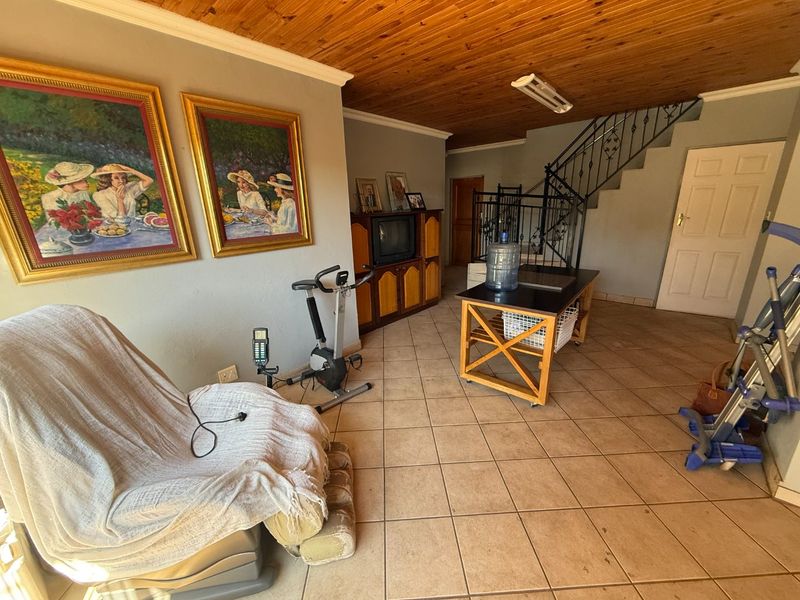 Living area featuring a timber ceiling, ceramic tiled flooring, and a wrought iron staircase railing leading to the upper level.