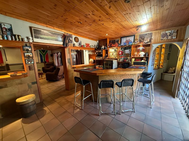 A dedicated home bar area featuring a built-in counter, timber-clad ceiling, and tiled flooring, providing a functional space for entertainment.