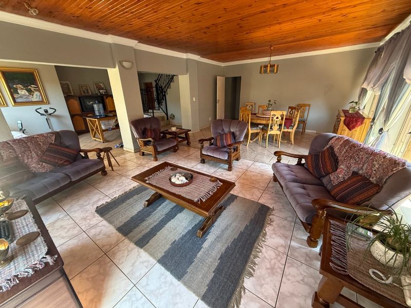 Spacious open-plan living and dining area featuring ceramic floor tiles and a traditional timber tongue and groove ceiling.