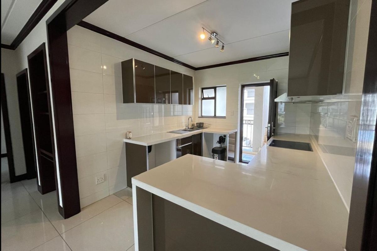 Modern kitchen featuring sleek built-in cabinetry, stone countertops, a hob, and tiled finishes, offering a clean and functional workspace.