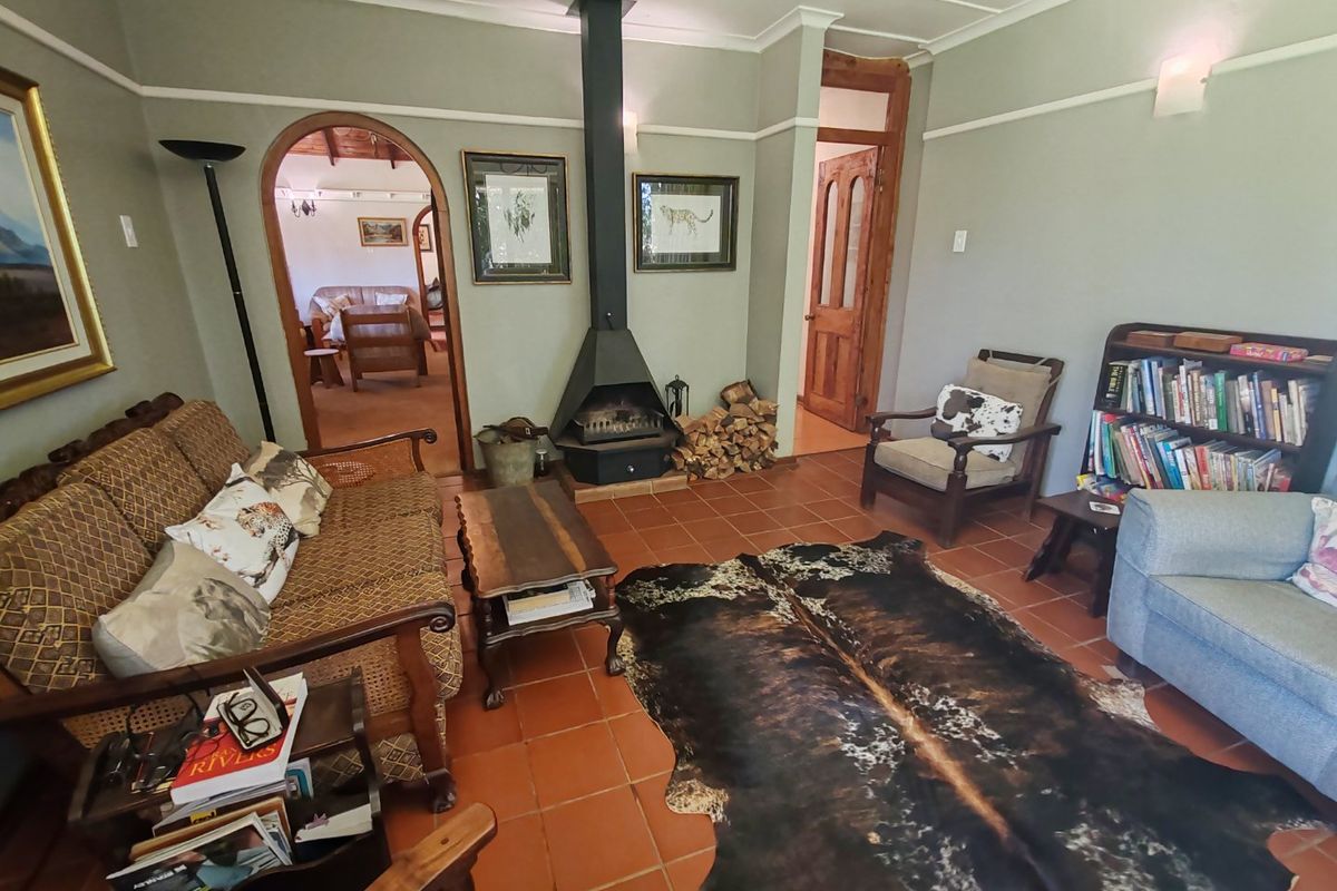 A cozy living room featuring terracotta floor tiles, a central freestanding fireplace, and an arched doorway leading to an adjacent living space.