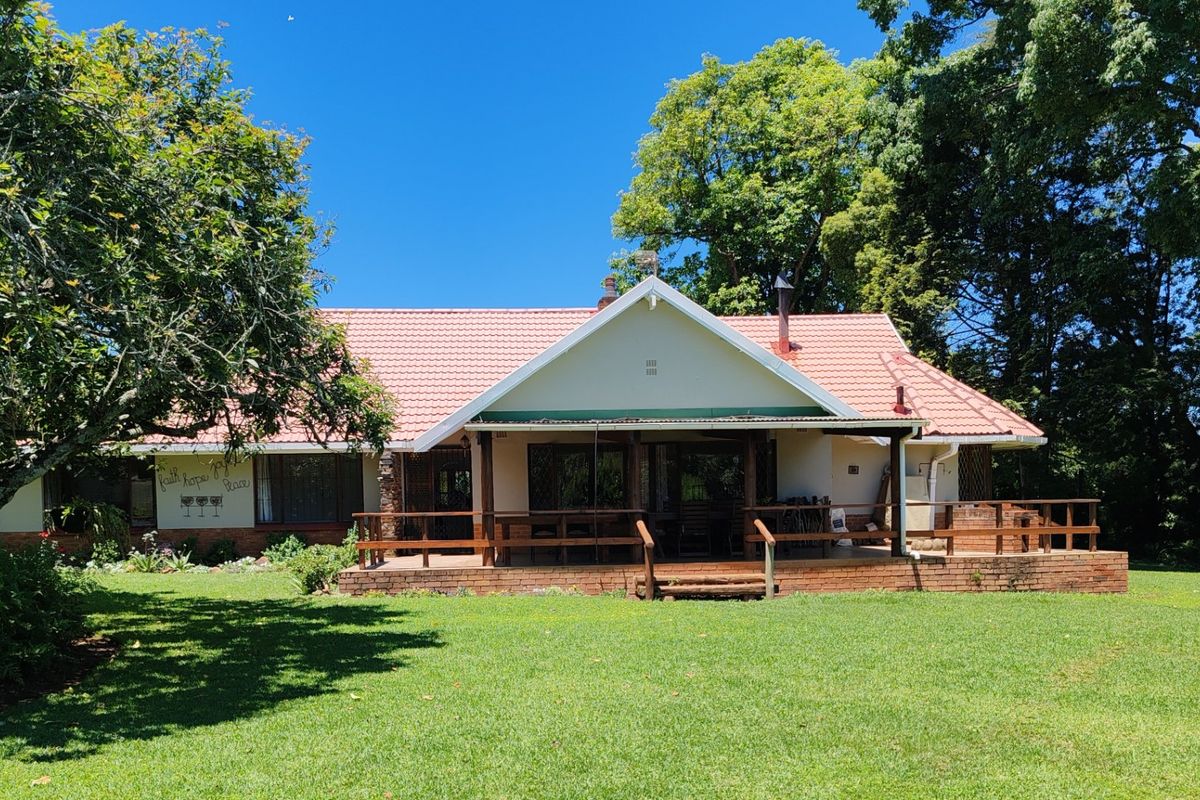 Rear view of a farm-style residence featuring a covered veranda, brick patio, and a well-maintained garden setting.