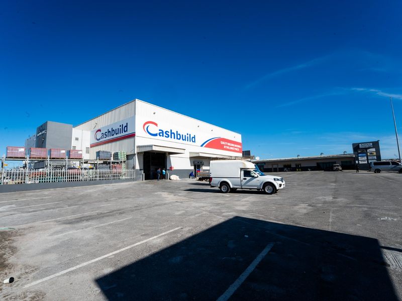 Commercial retail warehouse facility featuring a large asphalt parking area, metal cladding facade, and dedicated loading bay access.