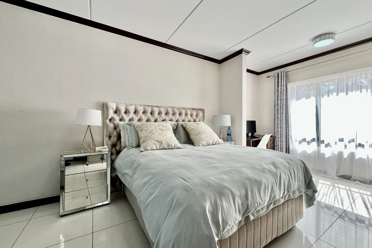 A well-lit bedroom featuring polished tile flooring, crown molding, and a sliding glass door providing natural light.