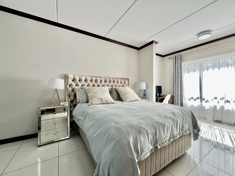 A well-lit bedroom featuring polished tile flooring, crown molding, and a sliding glass door providing natural light.