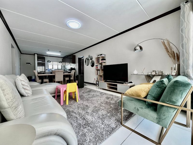 Spacious open-plan living and dining area featuring tiled flooring, modern ceiling lighting, and a functional kitchen layout.